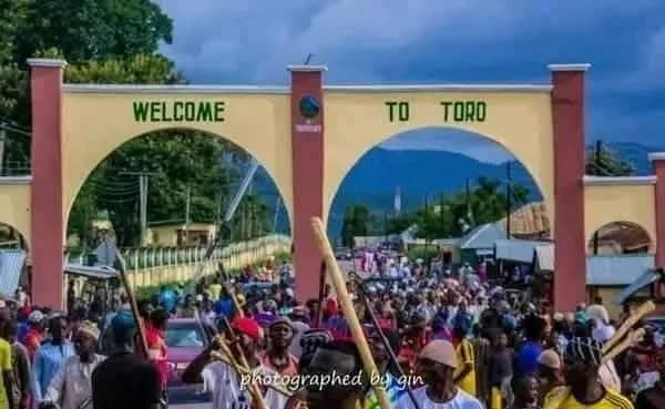 A crowd beneath the painted Welcome to Toro entrance gate.